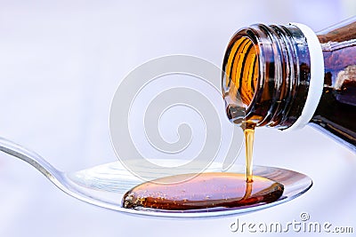 Hand pouring medication or antipyretic syrup from bottle Stock Photo