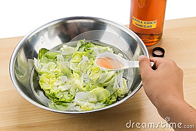 Hand pouring spoonful of Apple Cider Vinegar to soak and remove Stock Photo