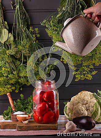 Hand pours boiling water into a banana with tomatoes. Stock Photo