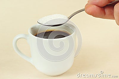 Hand pours sugar from spoon in a coffee cup Stock Photo