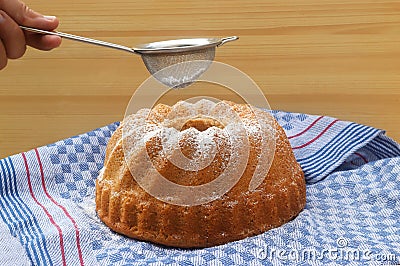 Hand powdering a traditional bundt cake with sugar Stock Photo