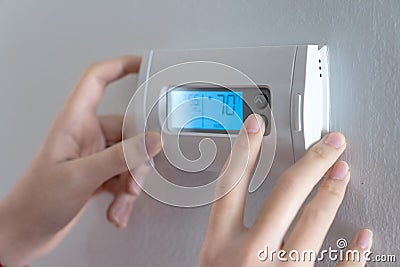 Hand press indoor room thermostat to lower the temp Stock Photo