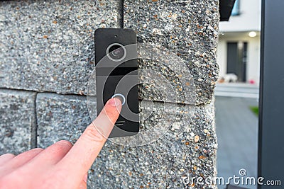 Hand pressing button of video intercom mounted on the stone wall Stock Photo