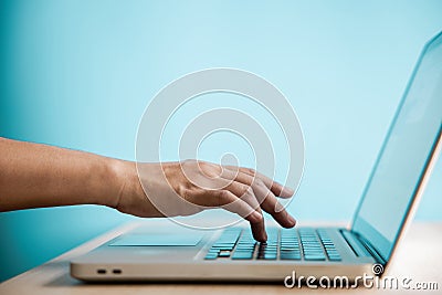 Hand Pressing Computer Keyboard. Side View. Closeup shot and Selective Focus on Finger. Person using Laptop for Working on Desk Stock Photo