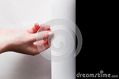 Hand pulling edge of paper to uncover, reveal something Stock Photo