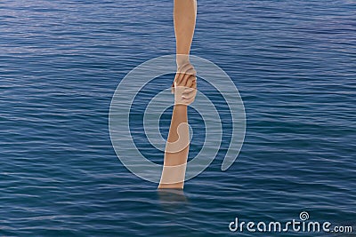 Hand pulling person from the sea Stock Photo