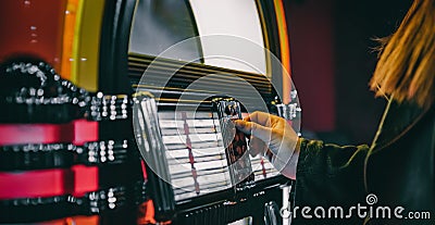 Hand pushing buttons to play song on old Jukebox, selecting records Stock Photo