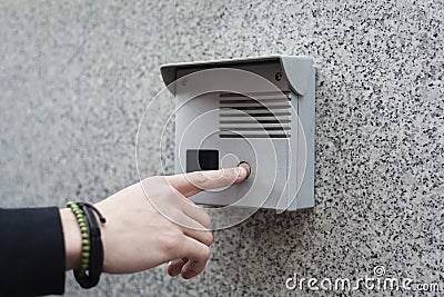 Hand pushing buzzer button on a wall Stock Photo