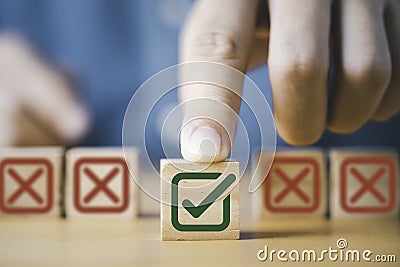 Hand pushing green correct sign symbol in front of Red Cross sign on wooden block cube for business proposal and document approve Stock Photo