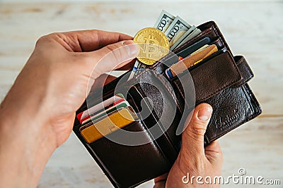 Hand put bitcoin in the wallet Stock Photo