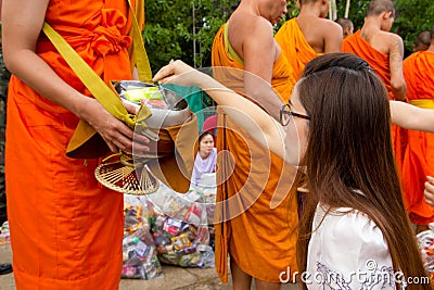 Hand while put food offerings in a Buddhist monk's alms bowl. f Editorial Stock Photo