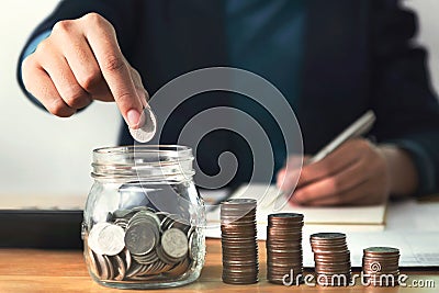 Hand puting money in jug glass Stock Photo