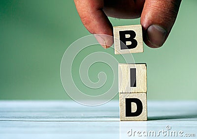 Hand puts the cube block with the inscription BID Stock Photo