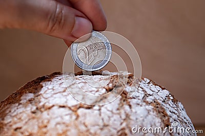 The hand puts the euro coin in the bread like in a money box. Economy, investment in food. food crisis. Agriculture. Agronomy. Stock Photo