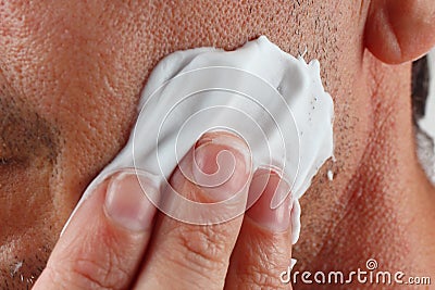Hand puts shaving foam on face closeup Stock Photo