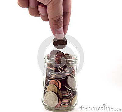 Hand putting coins in a glass jar Stock Photo