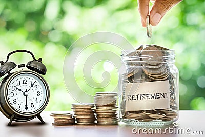 Hand putting Coins in glass jar Stock Photo