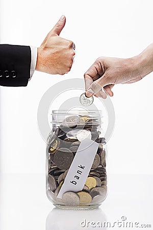 Hand putting Golden coins and seed in clear jar over white background Stock Photo