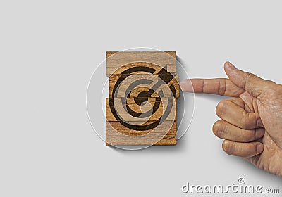 Hand putting the last piece of wooden blocks with the dart target icon on white background. Goal, business goal, achieving a goal Stock Photo