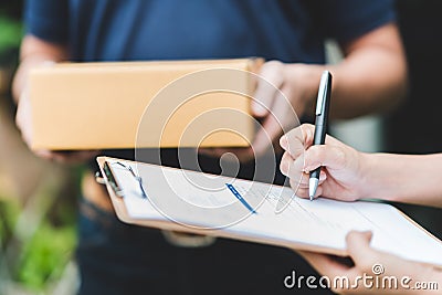 hand putting signature in clipboard to receive package from delivery man Stock Photo