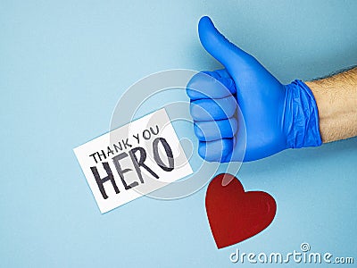 A hand with a raised thumb in a medical glove, a red heart and the inscription thank you to the heroes Stock Photo