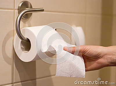 Hand reaches for toilet paper Stock Photo