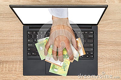 Hand reaching out of laptop screen to steal money Stock Photo