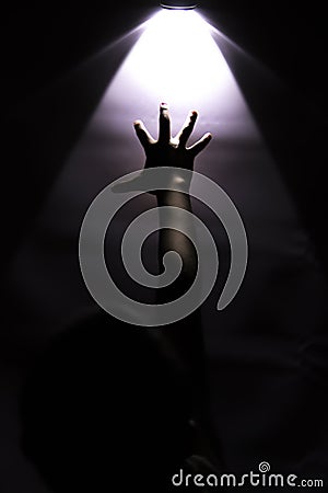 Hand reaching up to touch a glowing light Stock Photo