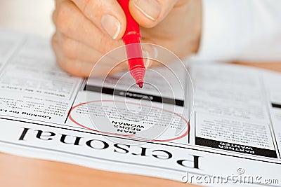 Hand with Red Pen Checking Personals in Newspaper Stock Photo