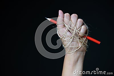Hand with red pencil tied with rope Stock Photo
