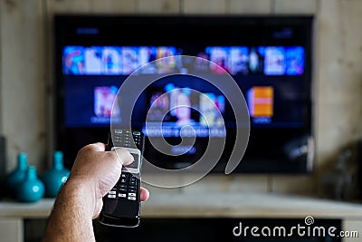 Hand with a remote control. Whats on tv, sliding through apps en movies on your television Stock Photo