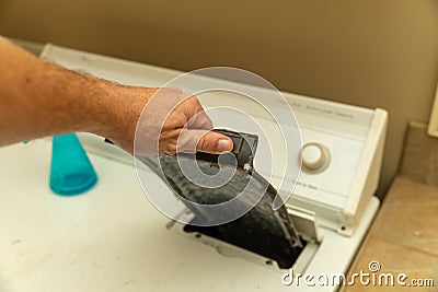 Hand removing dirty lint trap from dryer while doing laundry Stock Photo