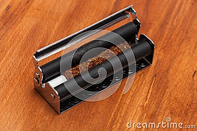 Hand rolling tobacco with the filter in the machine Stock Photo