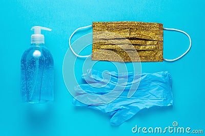 Hand sanitizer in a bottle with a gold medical face mask and gloves. Minimal Coronavirus outbreak. Pandemic concept Stock Photo