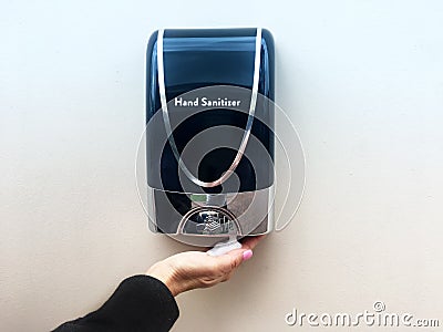 Hand sanitizer dispenser with hand underneath with sanitizing foam in palm Stock Photo