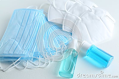 Hand sanitizers and respiratory masks on white table. Protective essentials during COVID-19 pandemic Stock Photo