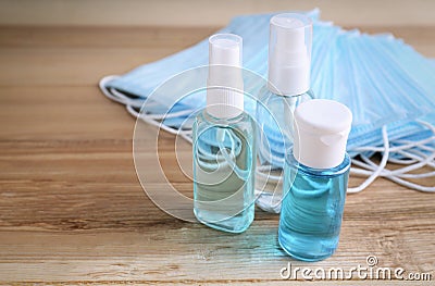 Hand sanitizers and respiratory masks on wooden table. Protective essentials during COVID-19 pandemic Stock Photo