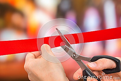 Hand with scissors cutting red ribbon - opening ceremony Stock Photo