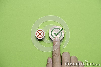 Hand select and touching to green correct sign mark between Red Cross mark which print screen on wooden cube block for approve and Stock Photo