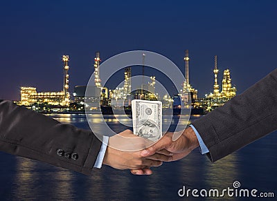 Hand shake between a businessman with dollar money on Petrochemical factory background Stock Photo