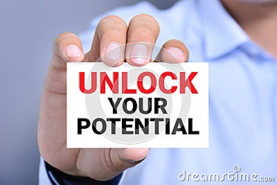 Hand showing card with message UNLOCK YOUR POTENTIAL Stock Photo