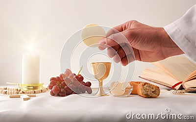 Hand showing a host on the altar with sacred objects Stock Photo