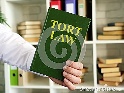 Hand shows a Tort law book in the office. Stock Photo