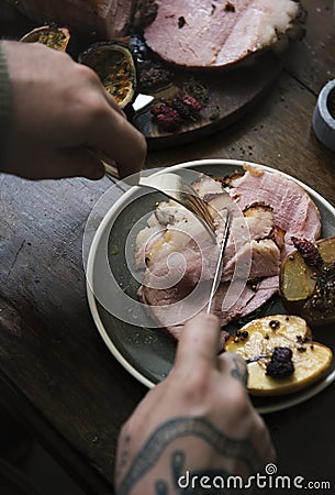 Hand slicing piece of ham Stock Photo
