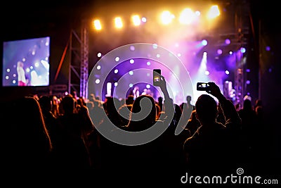 Hand with a smartphone records live music festival, Taking photo of concert stage, live concert, music festival Stock Photo