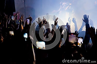 Hand with a smartphone records live music festival, Taking photo of concert stage. Party at nightclub with crowd of people raising Stock Photo