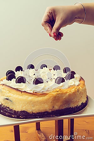 Hand sprinkling back biscuit on a cake Stock Photo