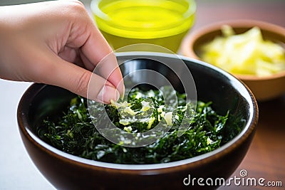 hand squeezing a lime over a bowl of seaweed salad Stock Photo