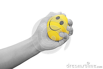 Hand squeezing smiling face yellow stress ball, isolated on white background Stock Photo