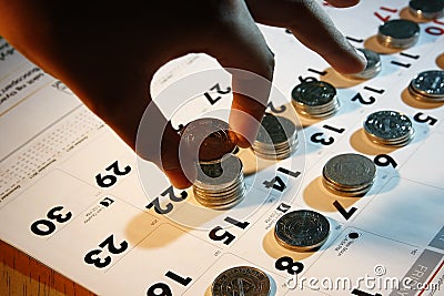 A Hand Stacking Coins/Money on A Calendar Stock Photo